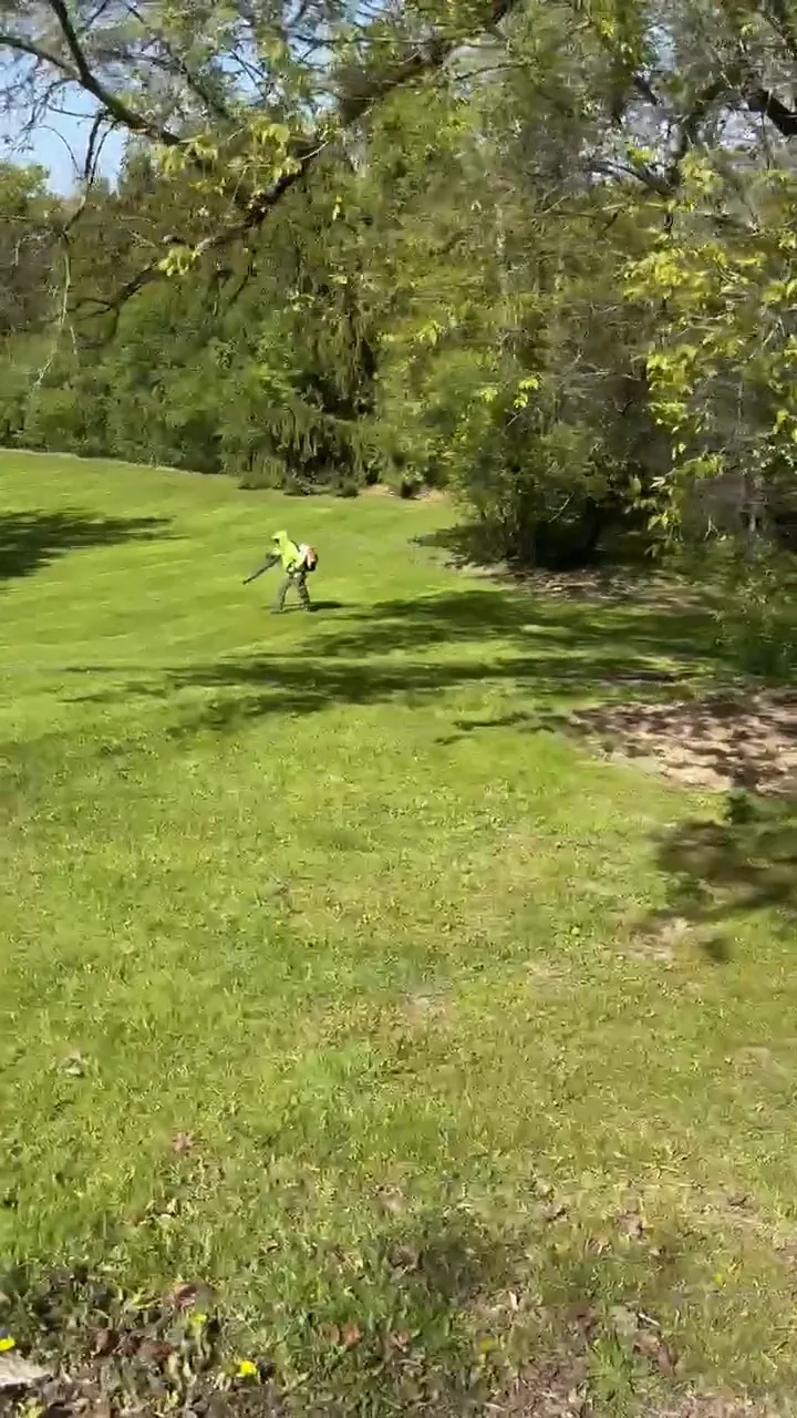 Crew member mowing a large open lawn into even stripes