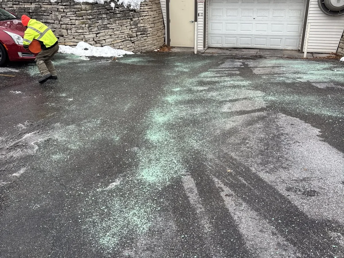 Crew member spreading ice melt on a cleared driveway