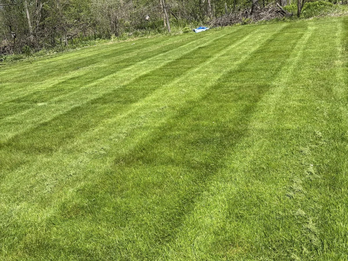 Large sloped lawn mowed in diagonal stripes with a consistent cut from top to bottom